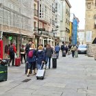 Un grupo de turistas con maletas por la calle de la Paloma.