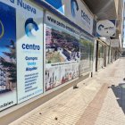 Una máquina barredora pasa junto al escaparate de una inmobiliaria.