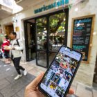 Una persona consulta con su móvil antes de entrar en un establecimiento de Burgos.