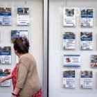 Una mujer se fija en los anuncios de inmuebles en el escaparate de una inmobiliaria de Burgos.