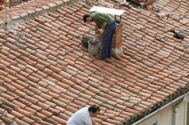 Dos hombres trabajan en la reparación de un tejado sin ningún tipo de sujeción.-ISRAEL L. MURILLO