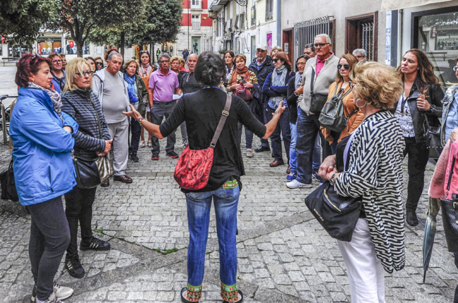 Un grupo de turistas atiende durante una ruta con guía turístico en Burgos.