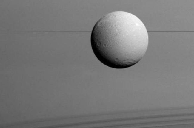 Panorámica de Dione con los anillos de Saturno al fondo.-Foto: NASA / ESA