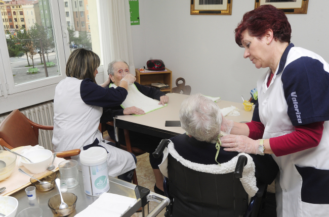 Dos trabajadoras ayudan a comer a dos ancianas. ISRAEL L. MURILLO