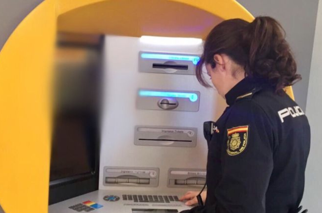 Una agente de la Policía Nacional inspecciona un cajero automático. ECB