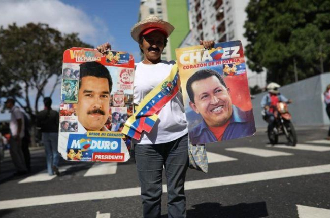 Una simpatizante de Maduro sostiene un cartel del mandatario y otro de Hugo Chávez  en una manifestación en Caracas.-RODRIGO ABD (AP)