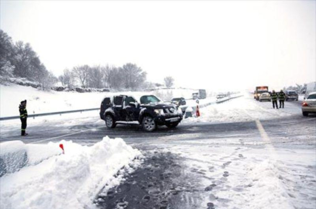 Agentes de la policía ayudan el domingo a los vehículos atrapados en la AP-6 por la tormenta de nieve.-EFE / LUISMI ORTIZ