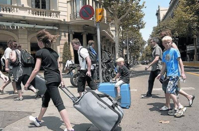 Turistas con maletas rumbo a su alojamiento recorren el paseo de Gràcia.-Foto:   JOAN CORTADELLAS