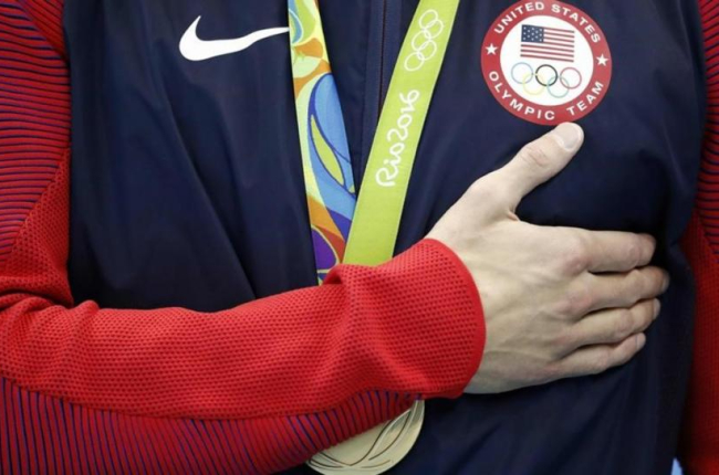 Michael Phelps se lleva la mano al pecho mientras suena el himno de EEUU, tras el triunfo en el relevo 4x100. La última de sus 28 medallas olímpicas.-AFP / ODD ANDERSEN