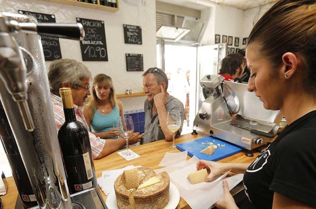 Una camarera prepara un trozo de queso a unos clientes. ECB