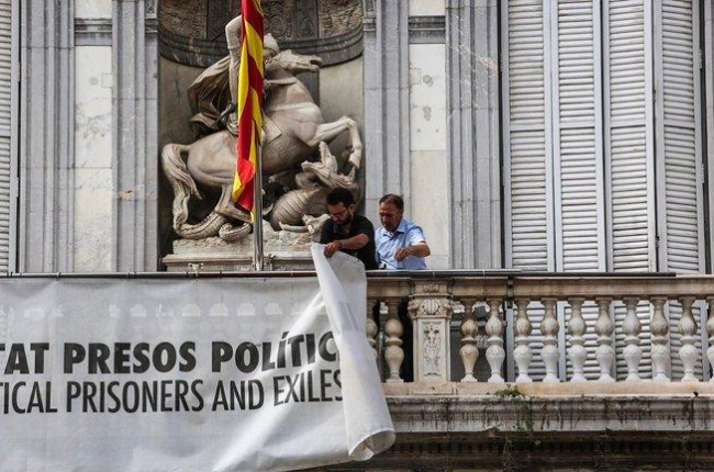 Dos trabajadores de la Generalitat retiran la pancarta que colgaba del Palau, el pasado 27 de septiembre.-ÁNGEL GARCÍA
