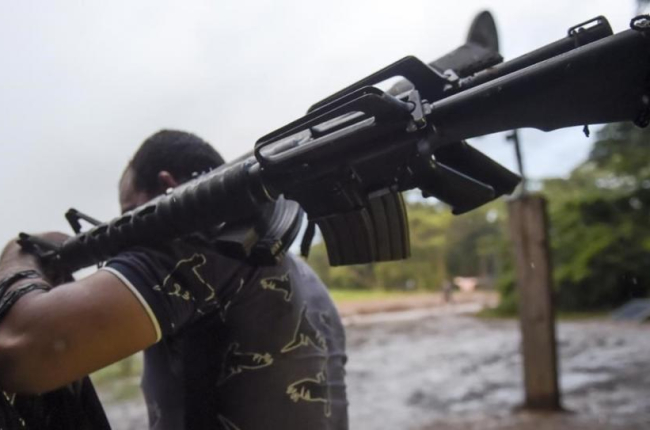 Un miembro de las FARC entrega un fusil de asalto.-AFP