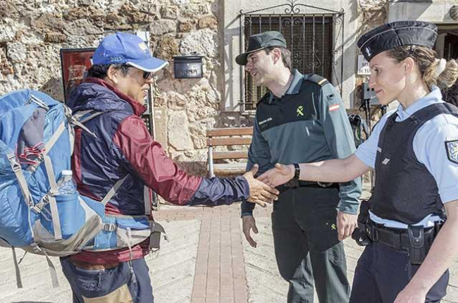 La gendarme Sofía Mateos y un agente de la Guardia Civil saludan a un peregrino en San Juan de Ortega.-SANTI OTERO