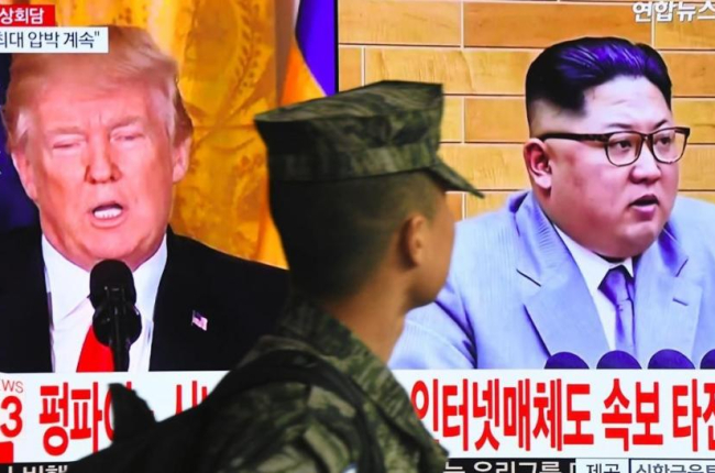 Un soldado surcoreano pasa frente a un televisor en Seúl mientras aparecen en la pantalla Donald Trump y Kim Jong un.-/ AFP / JUNG YEON-JE