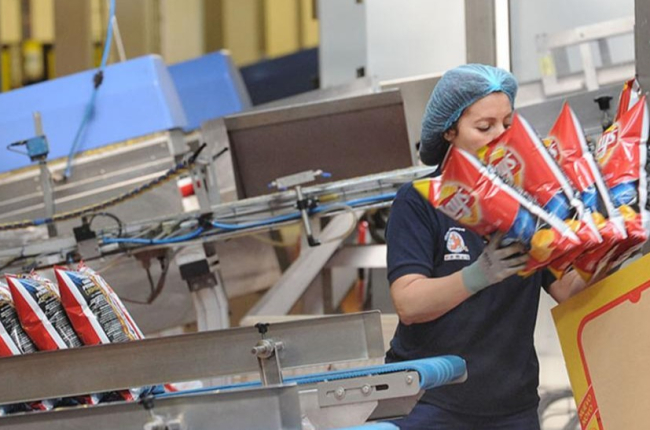 Una empleada realiza su trabajo en la línea de producción de una fábrica burgalesa de snacks.