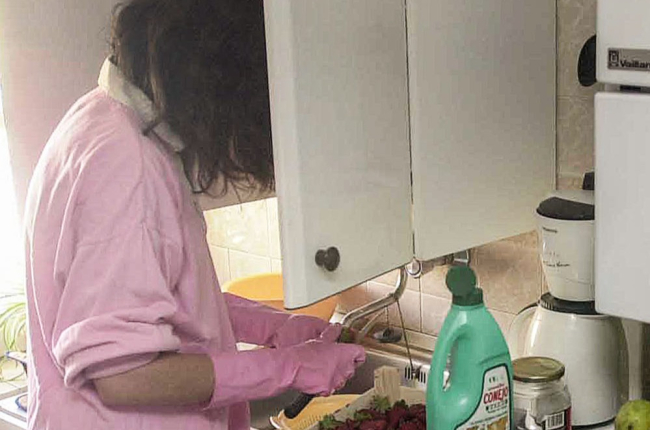 Una mujer limpia fruta en una cocina. ECB