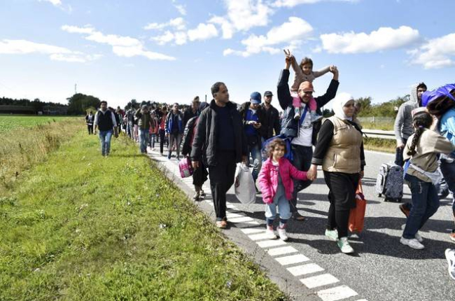 Un gran grupo de inmigrantes, sobretodo sirios, andan por una carretera en Dinamarca en dirección a Suecia, su destino.-REUTERS / SCANPIX DENMARK
