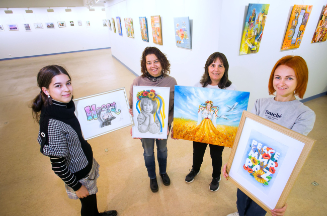Posan con sus obras Sofía Pavón, Anzhelika Svirska y Olesia Kotelevska. Les acompaña Virginia, una voluntaria del equipo que porta el cuadro de Olena Hontar. TOMAS ALONSO