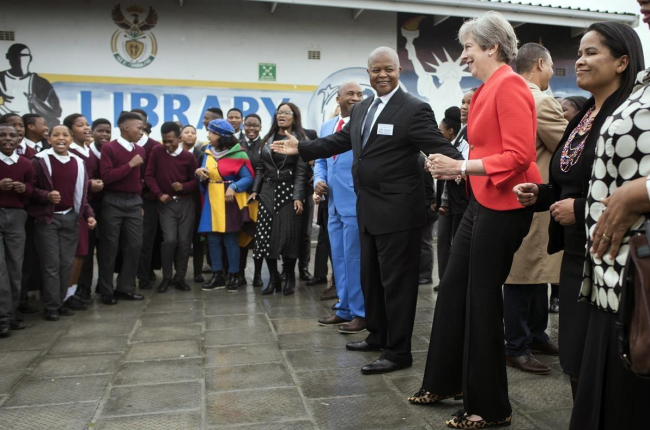 Theresa May, durante su visia a una escuela de Ciudad del Cabo, donde se ha arrancado a bailar. /-AP