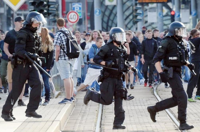 La policía alemana cruzando la calle en Chemnitz durante la polémica manifestación de caza de extranjeros.  /-ANDREAS SEIDEL