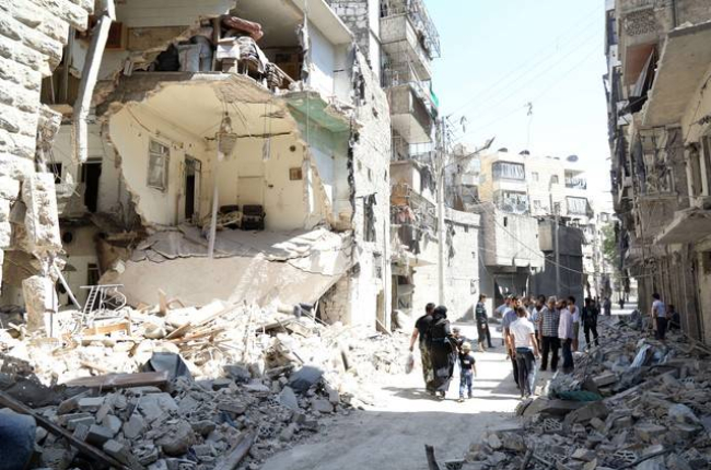 Vecinos de Alepo pasan junto a un edificio destruido en un bombardeo del régimen, este domingo.-Foto:   KHALED KHATEB / AFP / JALED JATEB