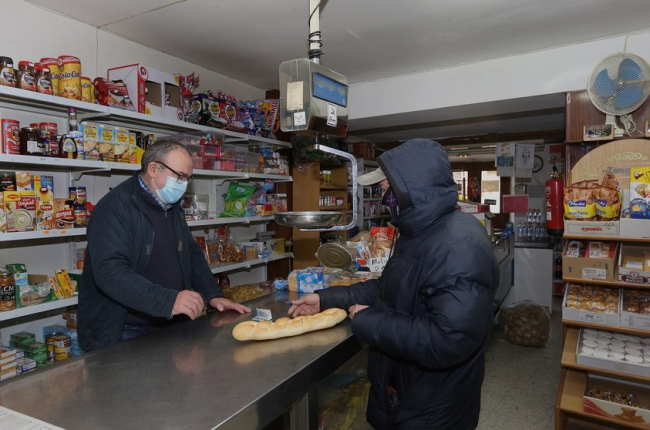 Un cliente compra pan en una tienda de alimentos y productos de primera necesidad en Amusco (Palencia).