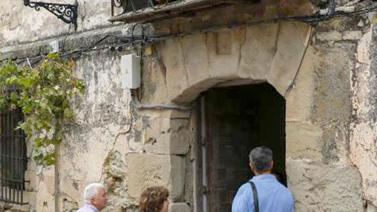 Tres visitantes esperan a la entrada de una casa rural.-ECB