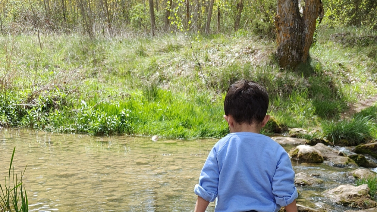 Un niño juega junto a un río.