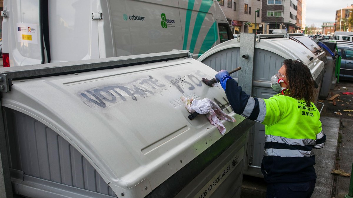 Una operaria de Urbaser limpia una pintada en un contenedor.