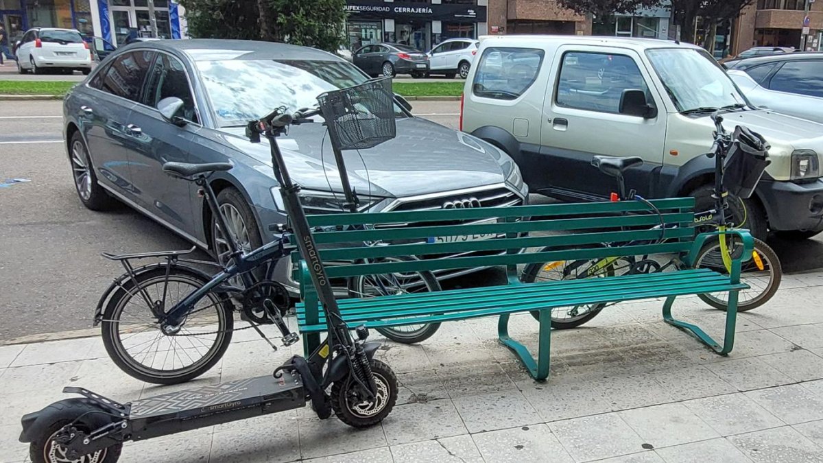 Bicis y patinete amarrados a un banco en la avenida de la Paz de Burgos.