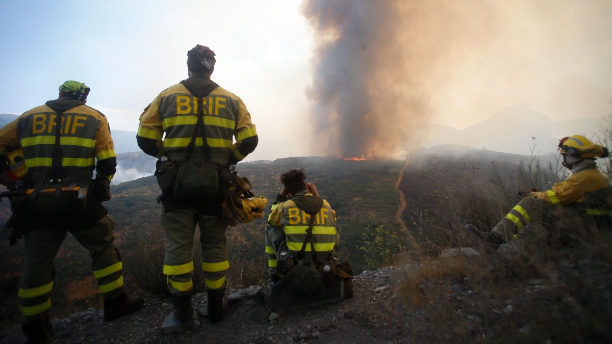 Varios bomberos observan el incendio forestal en La Baña.
