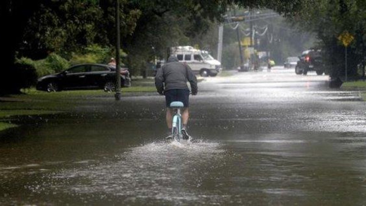 Un hombre circula con una bicicleta por una calle anegada en Beaumont (Tejas).-AP