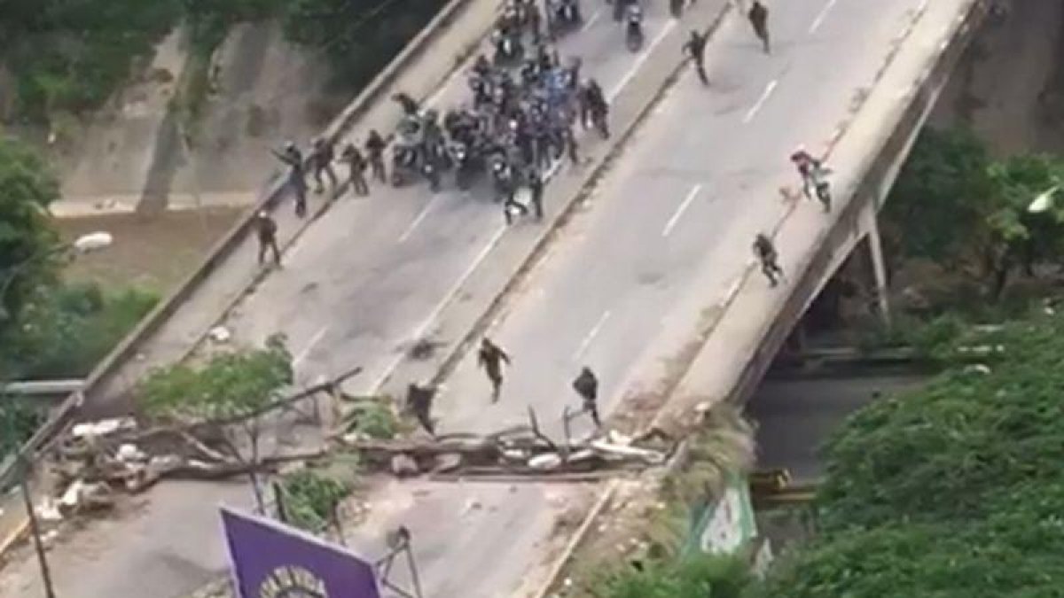 La policía venezolana irrumpe, en motos, para dispersar una manifestación.-EL PERIÓDICO