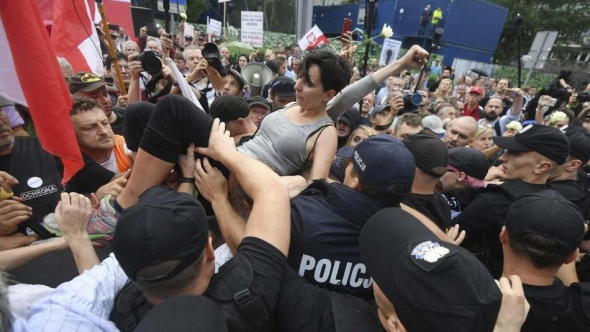 Un grupo de personas intentan romper la barrera formada por la policia durante una protesta en Polonia-BARTLOMIEJ ZBOROWSKI
