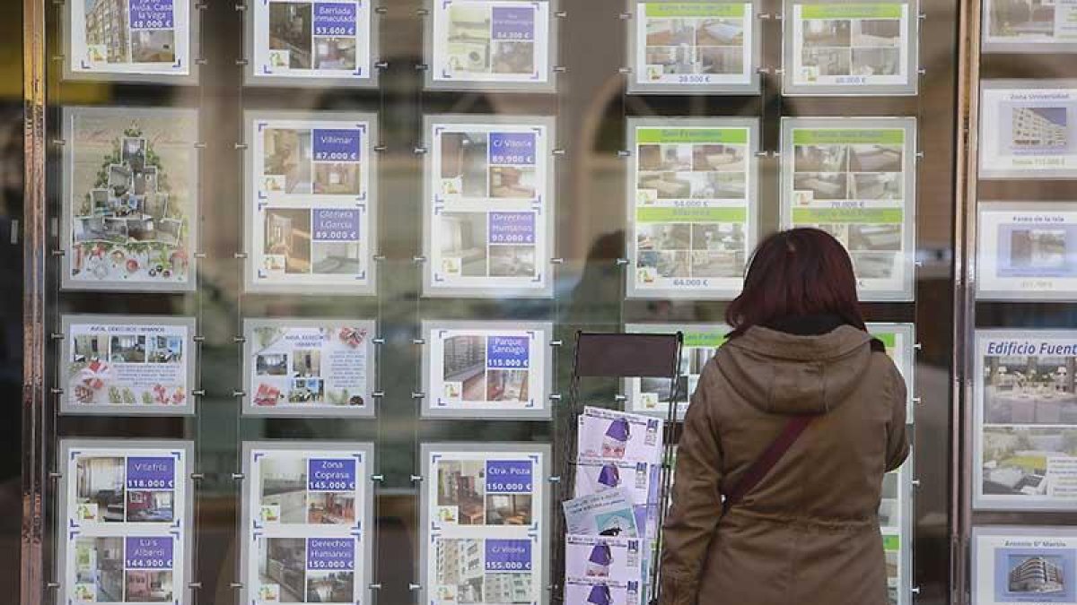 Una mujer observa un escaparate en una agencia inmobiliaria.-ISRAEL L. MURILLO