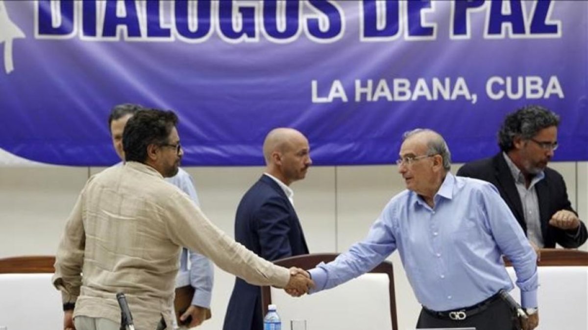El comandante de las FARC y líder del equipo negociador de paz Luciano Marin 'Ivan Marquez' estrecha la mano del jefe negociador del Gobierno colombiano Humberto de la Calle, el viernes.-ERNESTO MASTRASCUSA