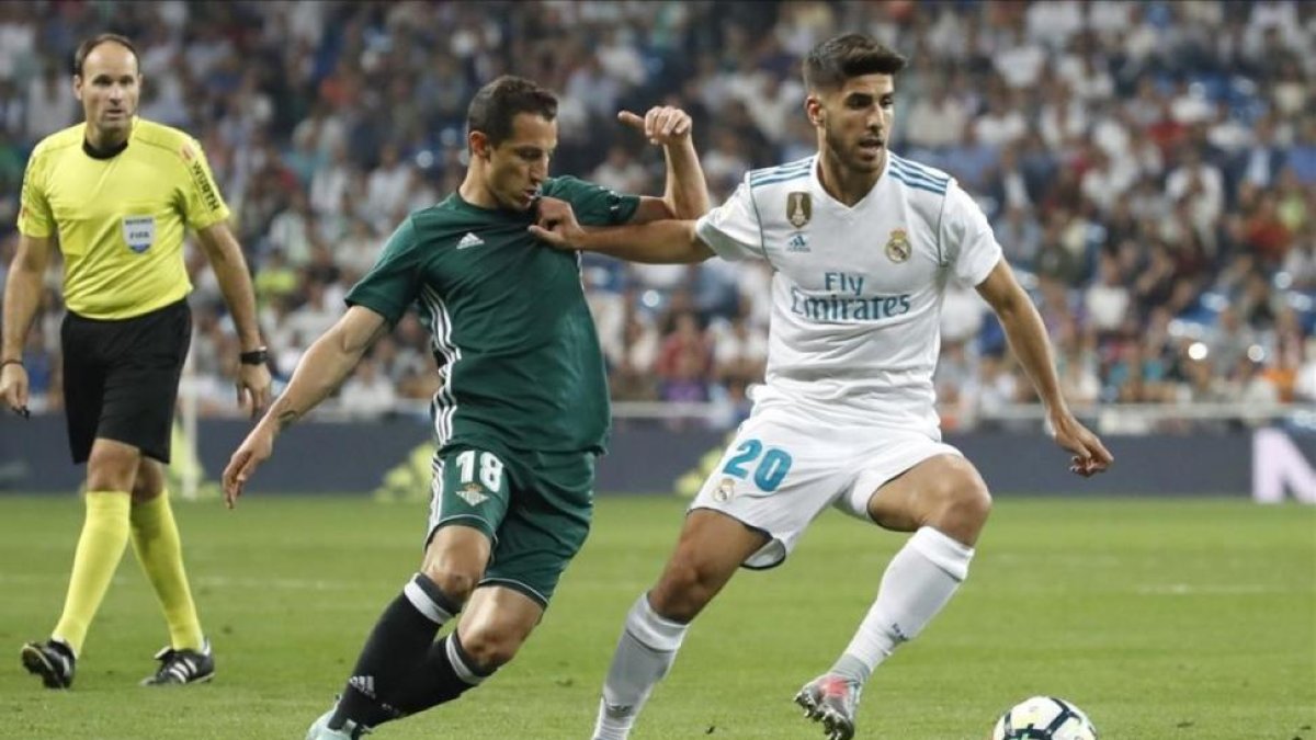 Asensio conduce el balón perseguido por Guardado durante el último Real Madrid-Betis.-JUANJO MARTÍN / EFE