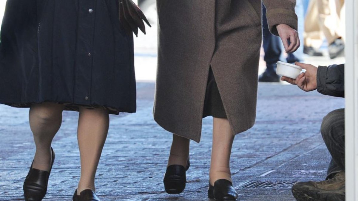 Dos mujeres depositan una limosna a una persona que pide en la calle.-ISRAEL L. MURILLO