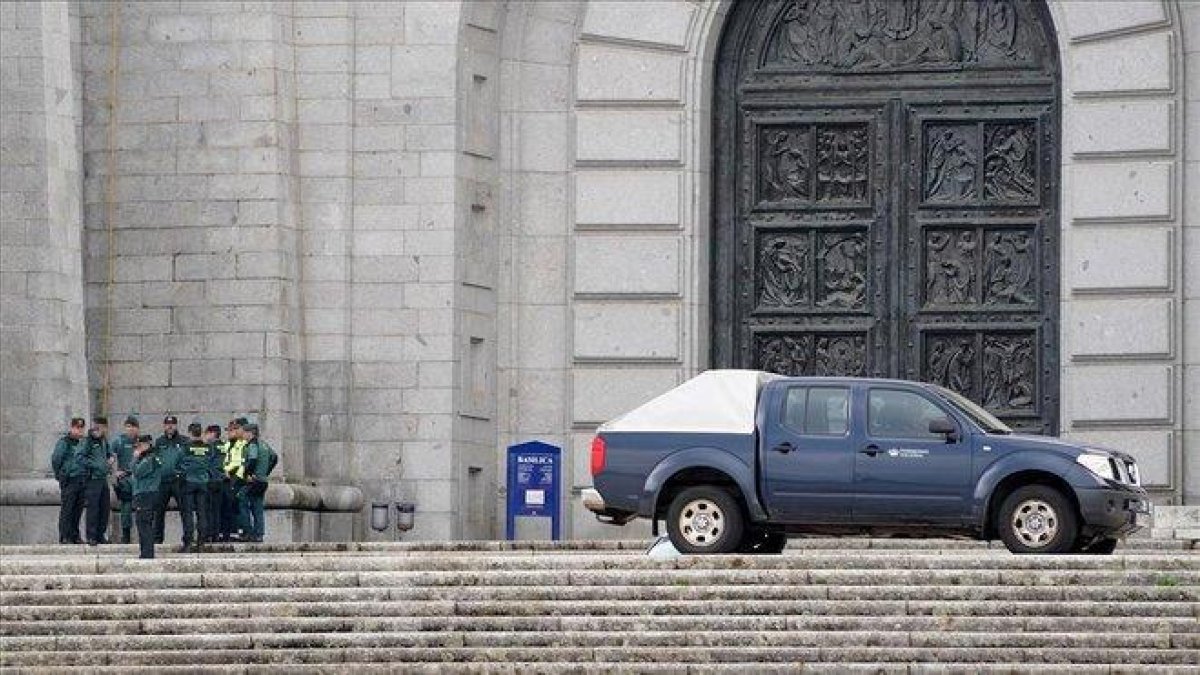 Un grupo de guardias civiles de los que han realizado preparativos esta mañana en la basílica del Valle de los Caídos, habla a la puerta de la basílica de la Santa Cruz junto a un coche de operarios de Patrimonio Nacional.-JOSÉ LUIS ROCA