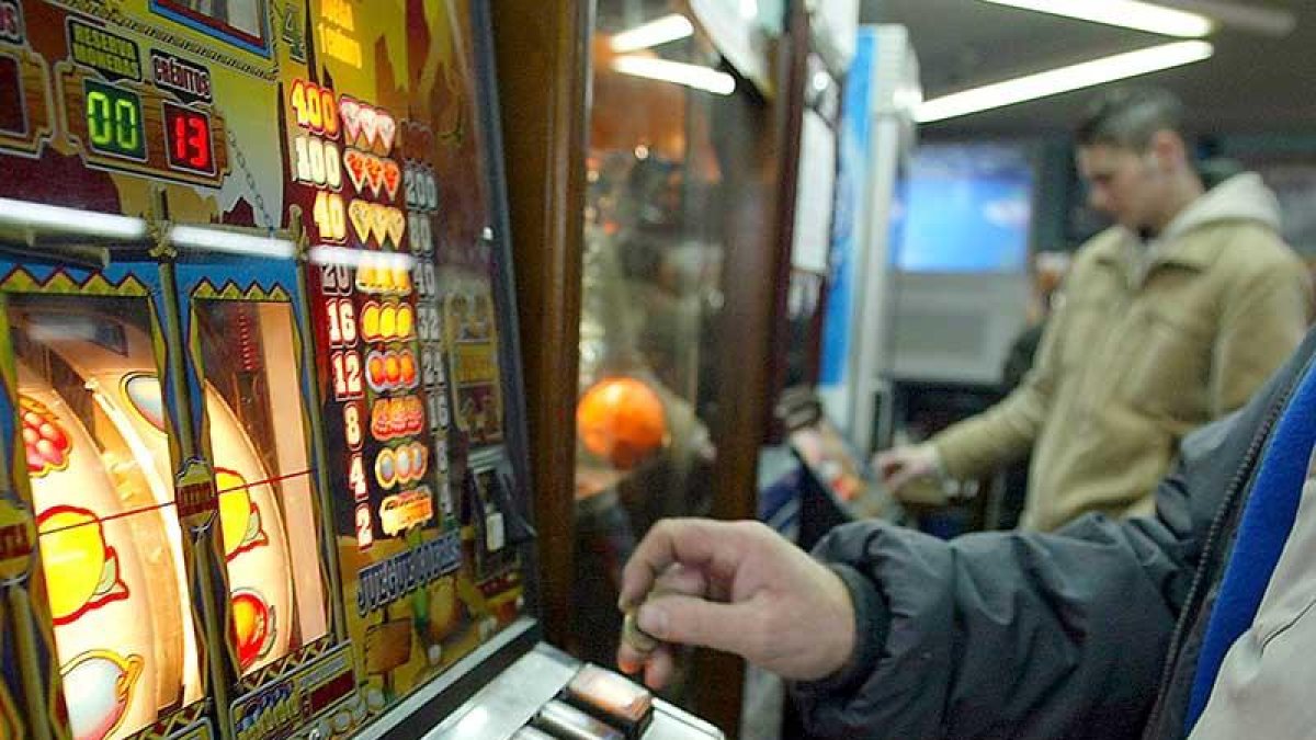 Varias personas gastan dinero en máquinas tragaperras en un local destinado a las apuestas y juegos de azar.-ICAL