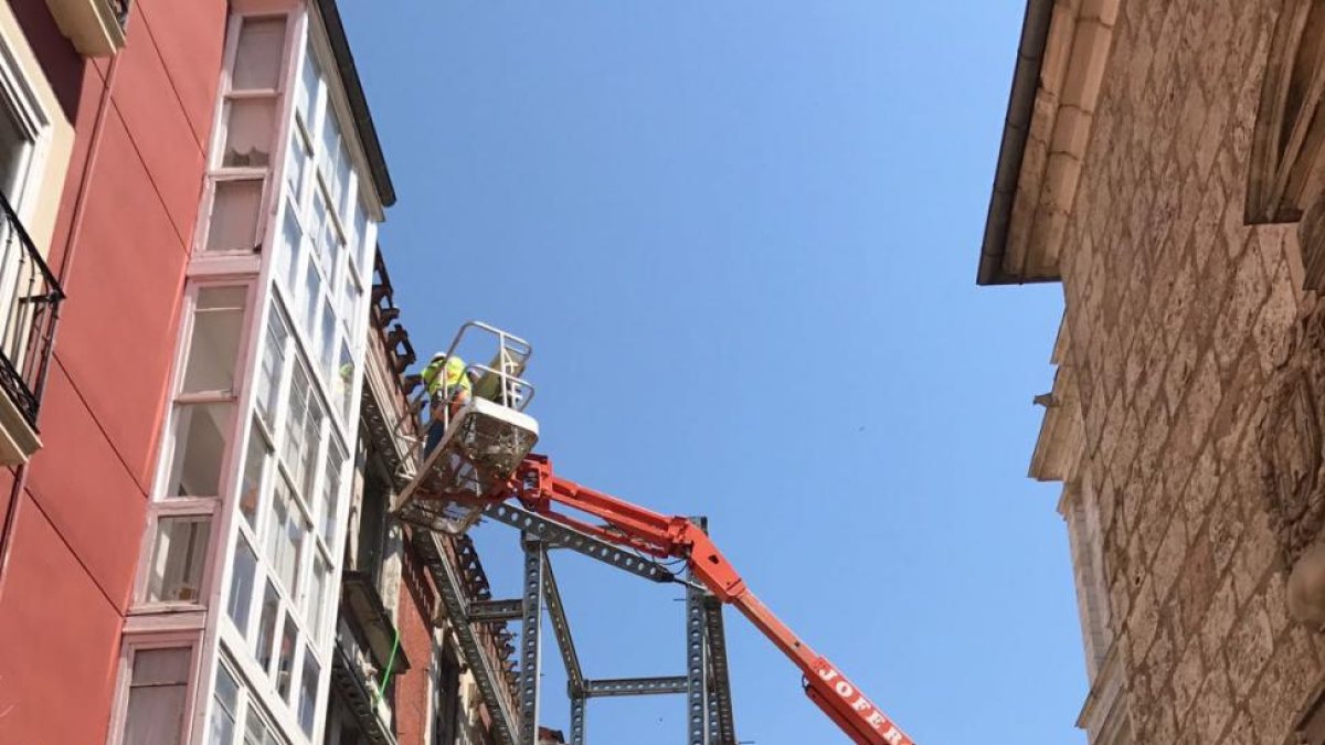 Los operarios desmontan el andamiaje desde una plataforma elevadora.-I. CASTILLA