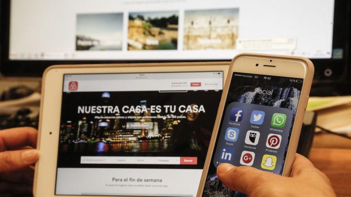 Un usuario consulta sus aplicaciones de redes sociales, en el móvil y en la tablet.-JULIO CARBÓ