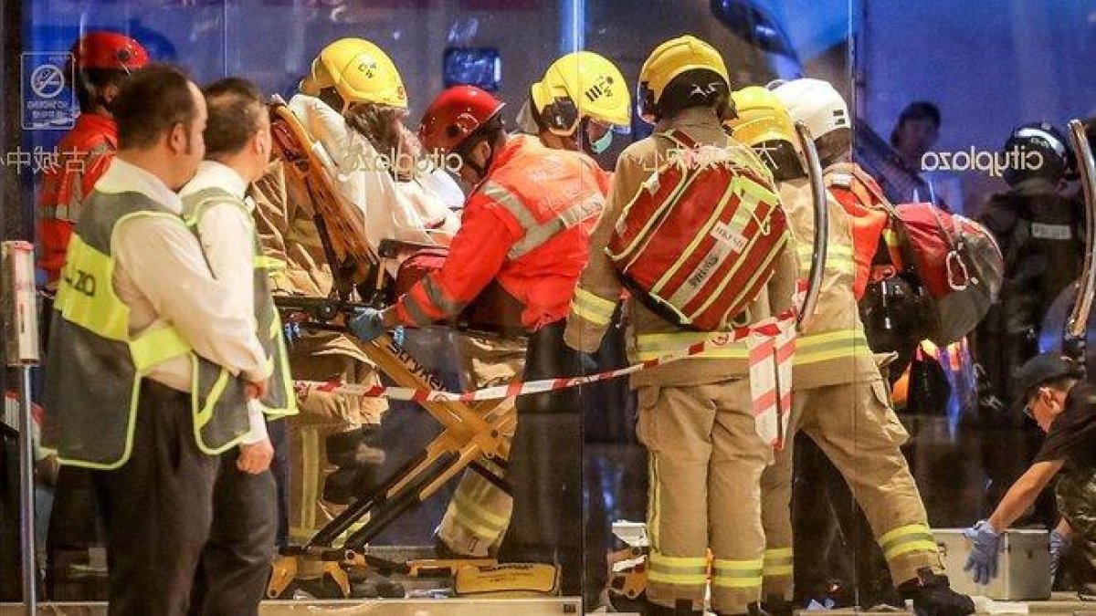 Personal sanitario traslada a una de las persona heridas en una sangrienta pelea con cuchillos en un centro comercial en Hong Kong, este domingo.-VIVEK PRAKASH (AFP)