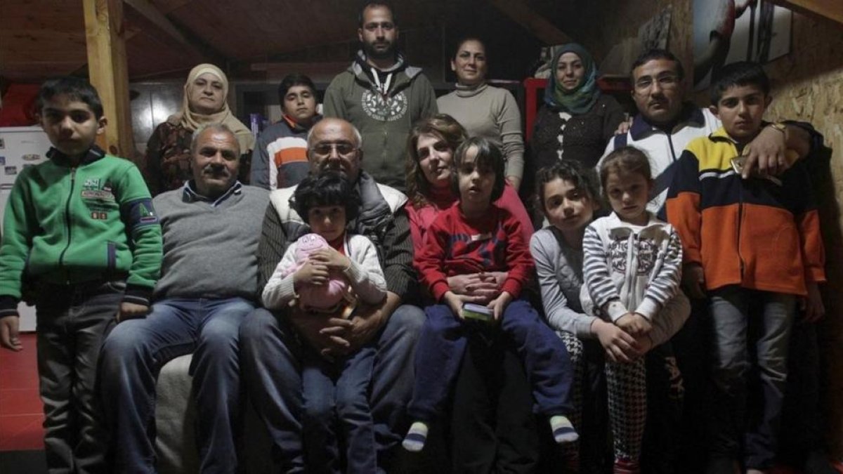 Dimitris Spiridis (en primera fila, tercero por la izquierda), junto a su mujer, Maria, y varios miembros de las dos familias sirias que acoge en su casa, en Evropos, cerca de Idomeni, este lunes.-REUTERS / ALEXANDROS AVRAMIDIS