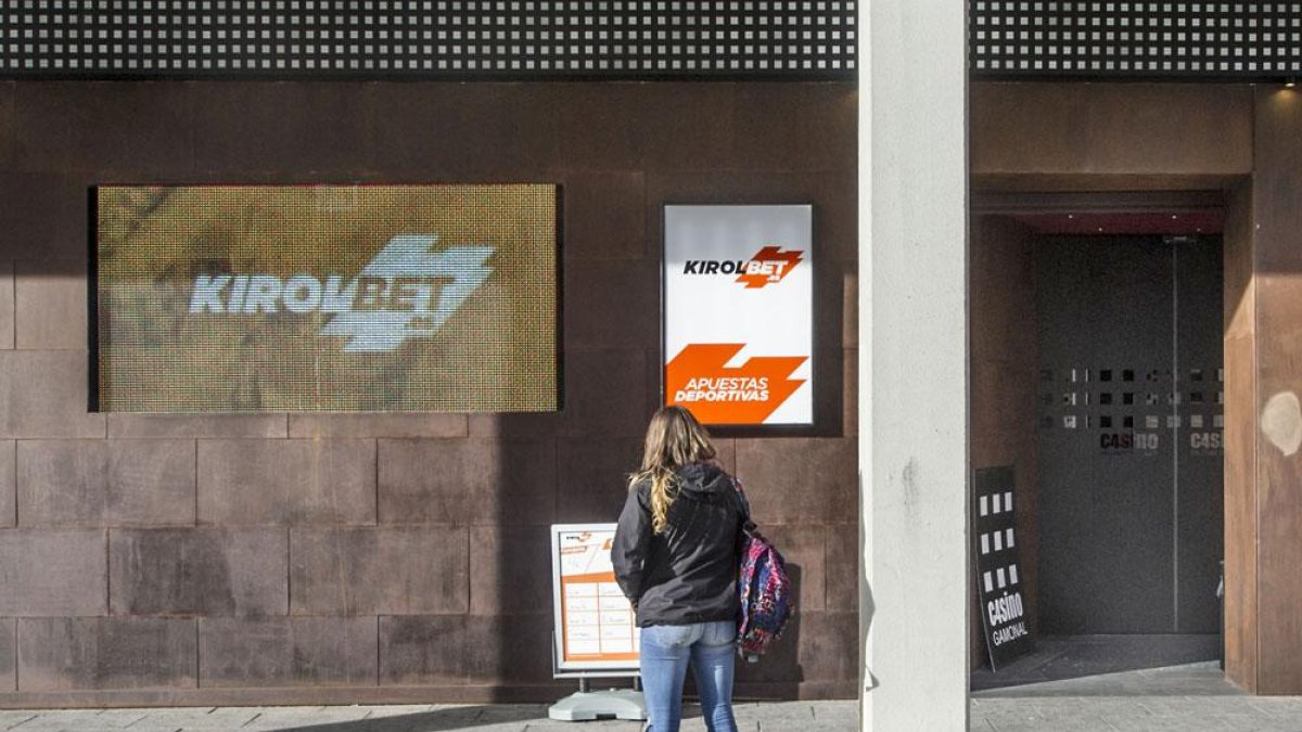 Una joven observa los carteles de las apuestas deportivas en la puerta de un local de Gamonal.