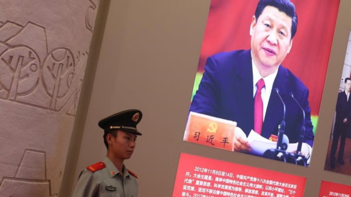 Un agente de policía permanece junto a una foto del presidente Xi Jinping, exhibida en una exposición sobre los logros de China en los últimos cinco años, en Pekín.-EFE / WU HONG