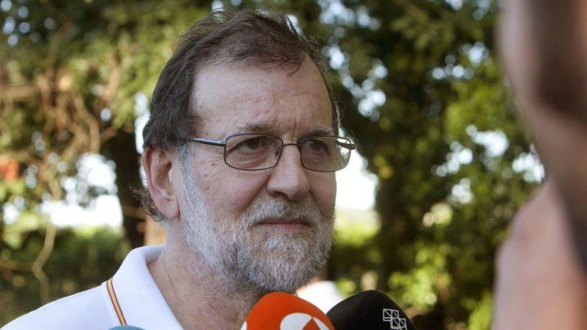 El presidente del Gobierno Mariano Rajoy atiende a los medios de comunicacion durante su paseo por las orillas del rio Umia a su paso por la localidad de Ponte Arnelas en Ribadumia Pontevedra en el inicio de sus vacaciones.-SALVADOR SAS (EFE)