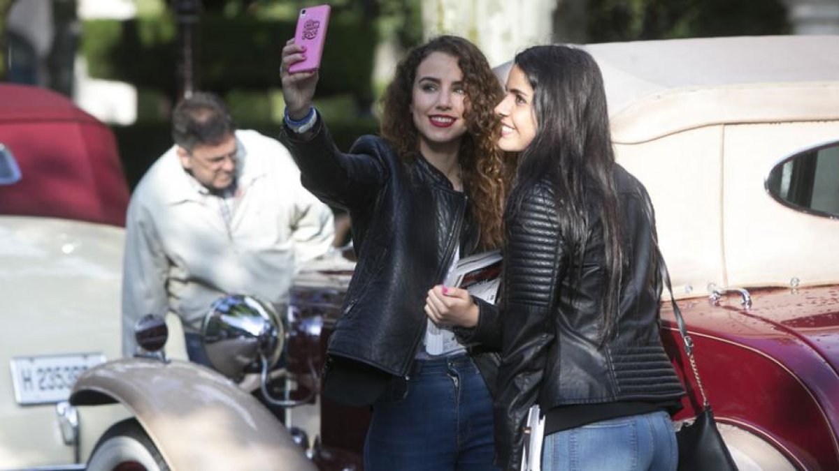 Dos chicas se hacen una foto con uno de los coches.-RAÚL G. OCHOA