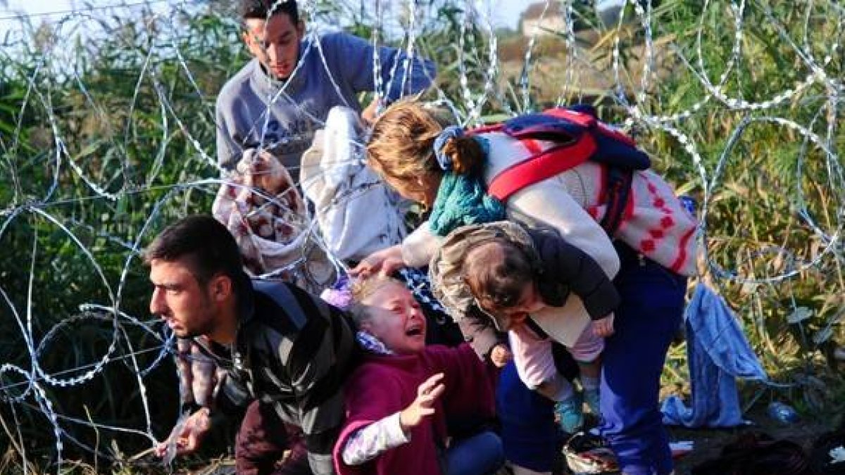 Una joven refugiada llora al quedársele el cabello enganchado en las púas de la concertina de la frontera de Hungría con Serbia.-AFP / ATTILA KISBENEDEK