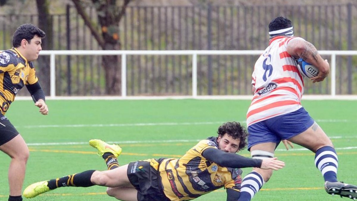 Juan Aristemuño se lanza a los pies del jugador del Universidad de Vigo Tatafu, ayer, en San Amaro.-ISRAEL L. MURILLO